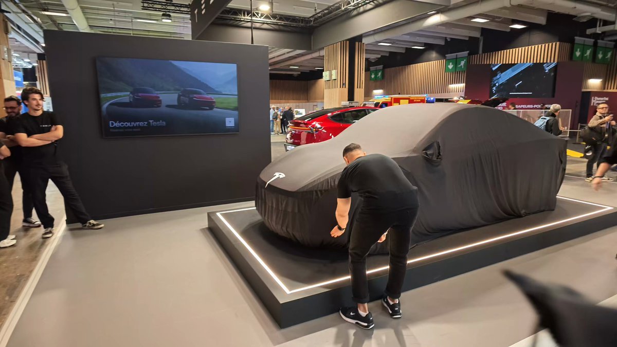 موظف من تسلا يزيح الغطاء الأسود عن سايبركاب في جناح تسلا بمعرض باريس للسيارات 2026